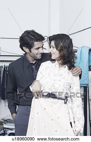 Stock Image - Young couple looking at outfits. Fotosearch
