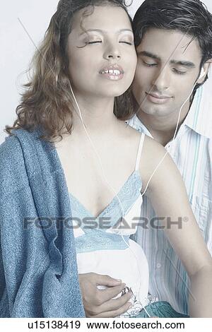 Stock Photo - Young couple wearing headphones listening to music. Fotosearch