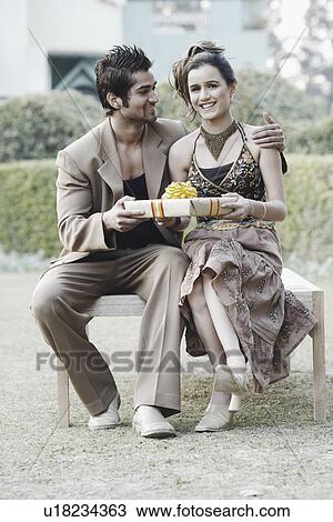 Stock Image - Young man giving a gift to a young woman. Fotosearch