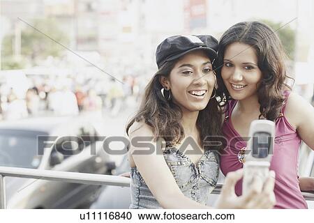 Close-up of two young women looking at a mobile phone View Large Photo Image Stock Image - Close-up of two young women looking at a mobile phone. Fotosearch