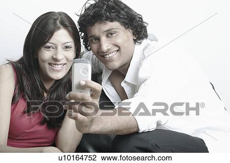 Young couple looking at a mobile phone View Large Photo Image Stock Image - Young couple looking at a mobile phone. Fotosearch