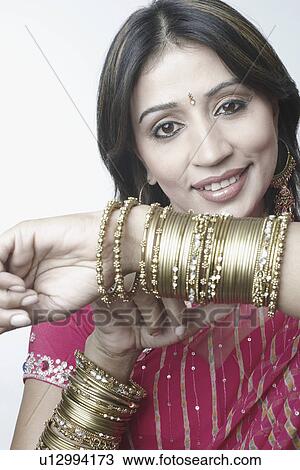 Stock Image - Portrait of a mid adult woman showing her bangles. Fotosearch