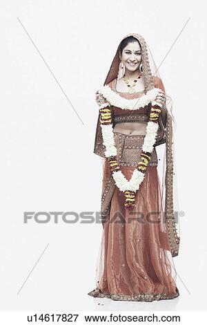 Stock Photo - Portrait of a young woman in traditional clothing holding a garland. Fotosearch