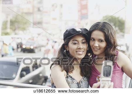 Close-up of two young women looking at a mobile phone View Large Photo Image Stock Photography - Close-up of two young women looking at a mobile phone. Fotosearch