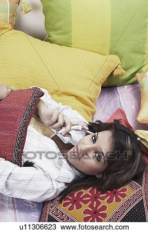 High angle view of a young woman lying down talking on a mobile phone View Large Photo Image Stock Image - High angle view of a young woman lying down talking on a mobile phone. Fotosearch