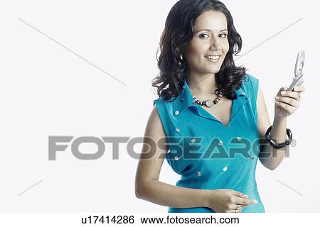 Portrait of a young woman holding a mobile phone View Large Photo Image Stock Photograph - Portrait of a young woman holding a mobile phone. Fotosearch