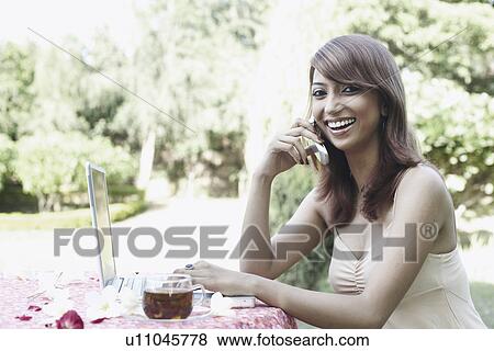 Stock Photo - Portrait of a young woman talking on a mobile phone. Fotosearch