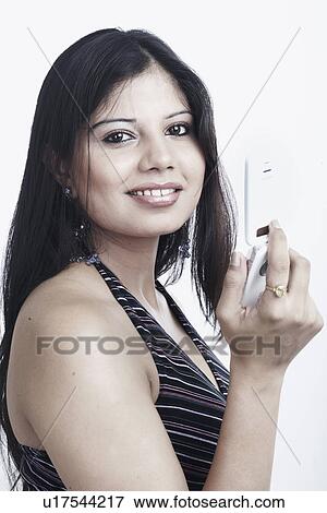 Stock Photo - Side profile of a young woman holding a mobile phone. Fotosearch