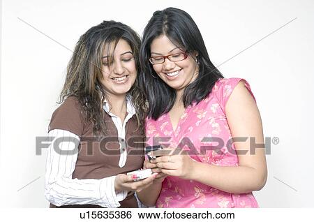 Stock Photograph - Close-up of two young women holding mobile phones. Fotosearch