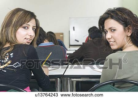 Stock Image - Portrait of two young women in a classroom. Fotosearch