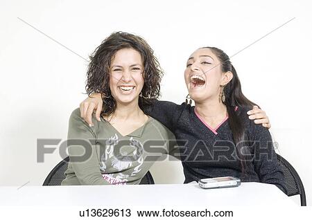 Stock Image - Portrait of two young women with their arms around each other. Fotosearch