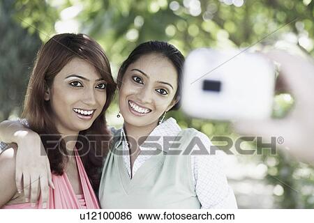 Young woman and a teenage girl posing in front of a camera View Large Photo Image Stock Photograph - Young woman and a teenage girl posing in front of a camera. Fotosearch