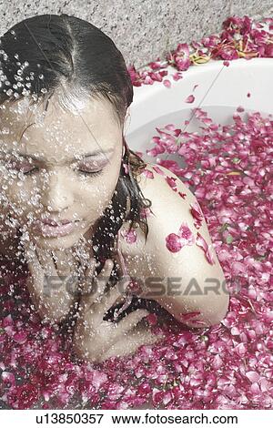 Stock Photo - Close-up of a young woman in a bathtub covered with flower petals. Fotosearch