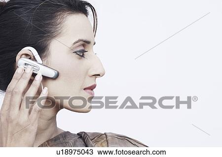 Stock Image - Close-up of a young woman wearing a hands free device. Fotosearch