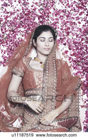 Stock Photo - High angle view of a young woman lying on rose petals. Fotosearch