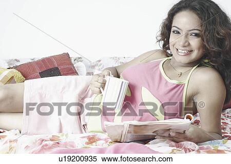 Stock Photography - Portrait of a young woman holding a cup and a magazine. Fotosearch