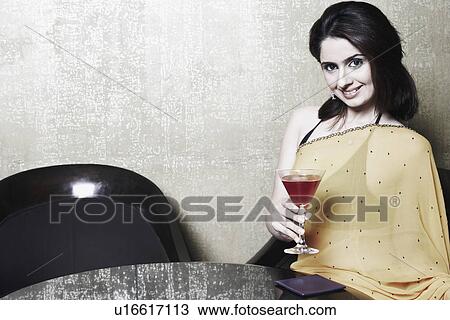 Portrait of a young woman holding a martini glass View Large Photo Image Stock Image - Portrait of a young woman holding a martini glass. Fotosearch