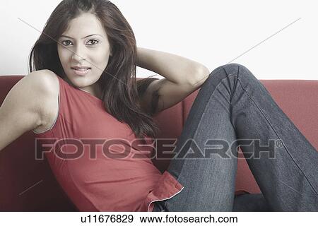 Stock Photo - Portrait of a young woman sitting on a couch. Fotosearch