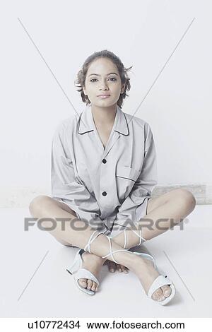 Portrait of a young woman sitting with her legs crossed View Large Photo Image Picture - Portrait of a young woman sitting with her legs crossed. Fotosearch