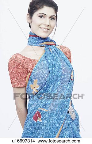 Picture - Portrait of a young woman standing with her hands behind her back. Fotosearch