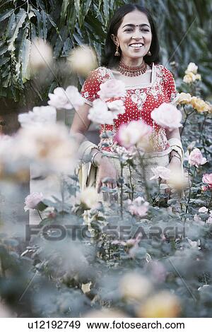 Stock Photo - Young woman standing in the garden. Fotosearch