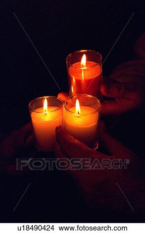 Picture - Three hands holding burning candles. Fotosearch