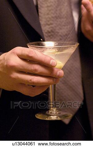 Business man holding martini cocktail at social gathering View Large Photo Image Stock Image - Business man holding martini cocktail at social gathering. Fotosearch