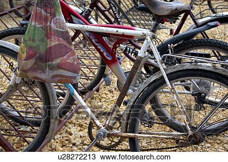 Stock Image - Bicycles parked in racks with grocery bag. Fotosearch