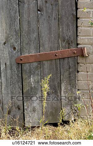 Stock Image - Door with large rusty hinge on polish farm. Fotosearch