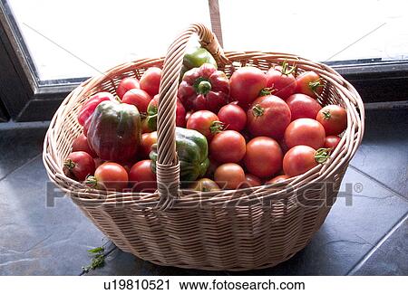 Stock Image - Freshly picked basket of tomatoes and peppers on kitchen sideboard. Fotosearch