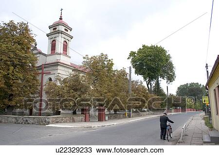 Stock Image - Polish man bicycle and catholic church. Fotosearch