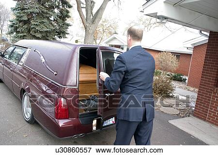 Stock Photo - Funeral director closing back door of hearse on coffin. Fotosearch