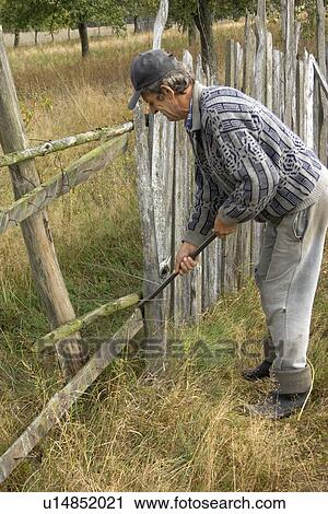 Stock Image - Farmer repairing his fence.. Fotosearch