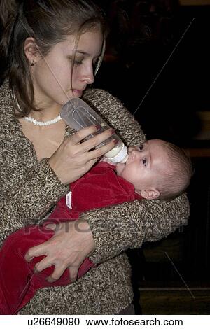 Cousin age 13 feeding baby boy with a bottle of milk View Large Photo Image Stock Image - Cousin age 13 feeding baby boy with a bottle of milk. Fotosearch