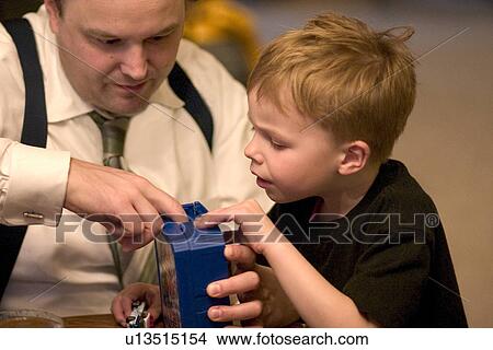 Picture - Dad trying to help son solve the mystery of a childhood toy. Fotosearch
