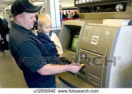 Stock Image - Father showing son ways of the modern world by withdrawing cash at the ATM machine. Fotosearch