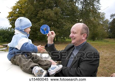 Stock Photography - Grandfather showing grandson a disk. Fotosearch