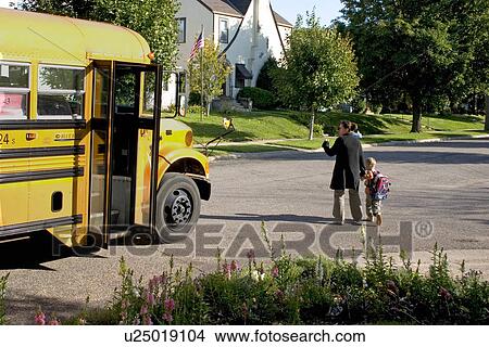 Mom walking son across street and waving goodby to school bus drive View Large Photo Image Picture - Mom walking son across street and waving goodby to school bus drive. Fotosearch