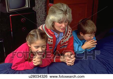 Stock Photograph - Mother and children praying together before bedtime. Fotosearch