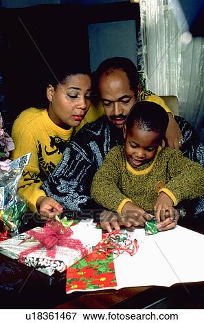 Stock Photo - Parents helping son wrap Christmas gifts. Fotosearch