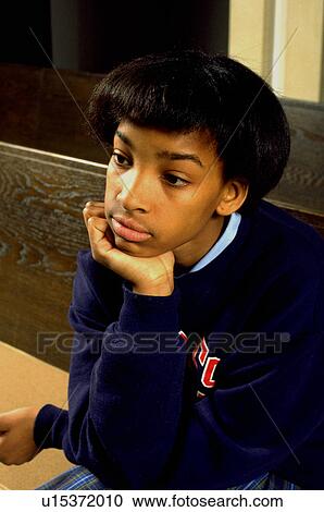 Stock Image - Girl age 13 thinking in church pew with chin in hand. Fotosearch