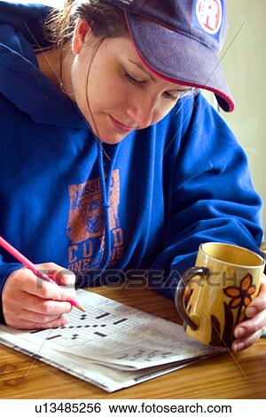 Woman age 35 working crossword puzzle holding coffee mug View Large Photo Image Stock Photograph - Woman age 35 working crossword puzzle holding coffee mug. Fotosearch