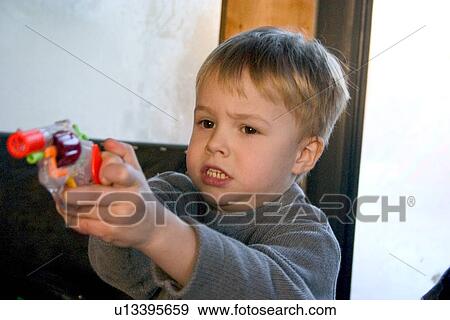 Stock Photo - Boy age 4 aiming colorful toy cap gun. Fotosearch
