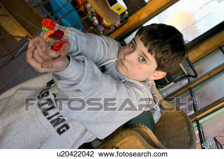 Stock Image - Boy age 8 aiming colorful toy cap gun. Fotosearch