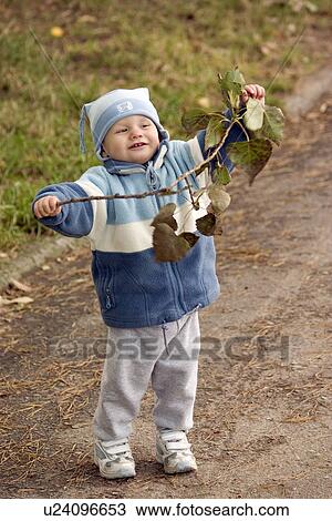 Stock Image - Happy toddler holding a branch of leaves. Fotosearch