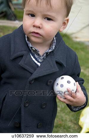 Stock Photo - One year old boy suspiciously clutching his whiffle ball. Fotosearch