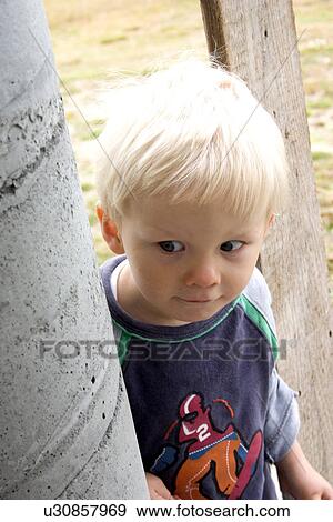 Stock Photo - Toddler quizzically looking around post. Fotosearch