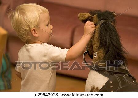 Stock Photograph - Toddler touching his rocking horse. Fotosearch