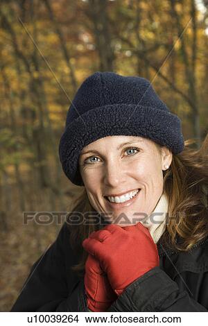 Head and shoulder portrait of smiling Caucasian woman in hat and gloves in woods. View Large Photo Image Picture - Head and shoulder portrait of smiling Caucasian woman in hat and gloves in woods.. Fotosearch