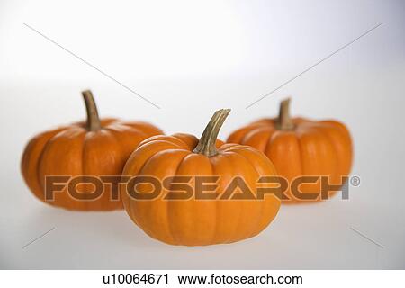 Stock Image - Still life of three orange pumpkins against white background.. Fotosearch